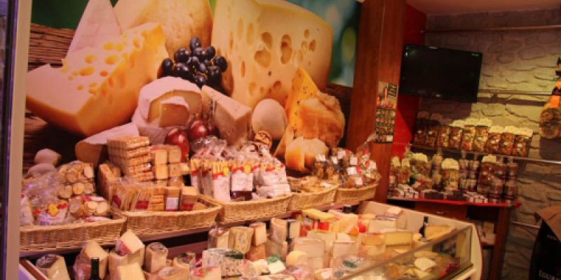 Expositor amb formatges i vinil decoratiu a paret a l'interior de la botiga vist des de l'esquerra