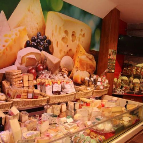 Expositor con quesos y vinilo decorativo en pared en el interior de la tienda visto desde la izquierda