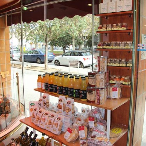 Imatge d´interior de la botiga amb aparador al fons i expositor amb productes en primer pla