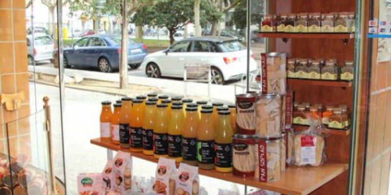 Imagen de interior de la tienda con escaparate al fondo y expositor con productos en primer plano